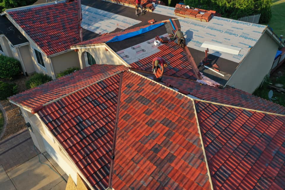 Workers installing tiles on roof 