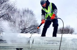 A man using a steamer to remove ice dams